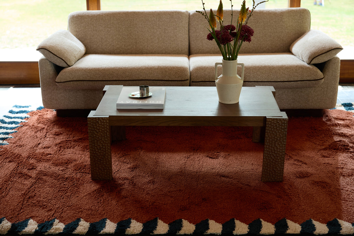 table basse Maxence en bois à pieds sculptés - vue de trois-quarts sur tapis terracotta