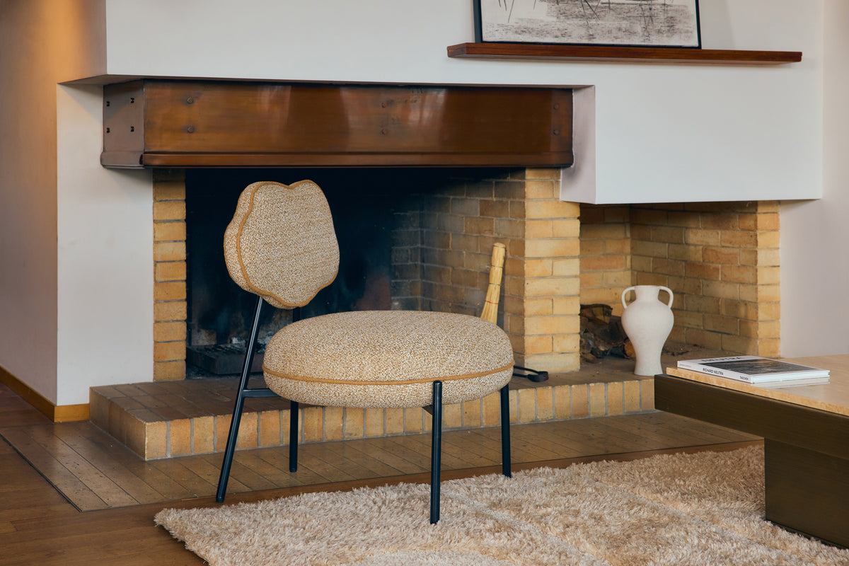 fauteuil arty jaune moucheté devant une cheminée