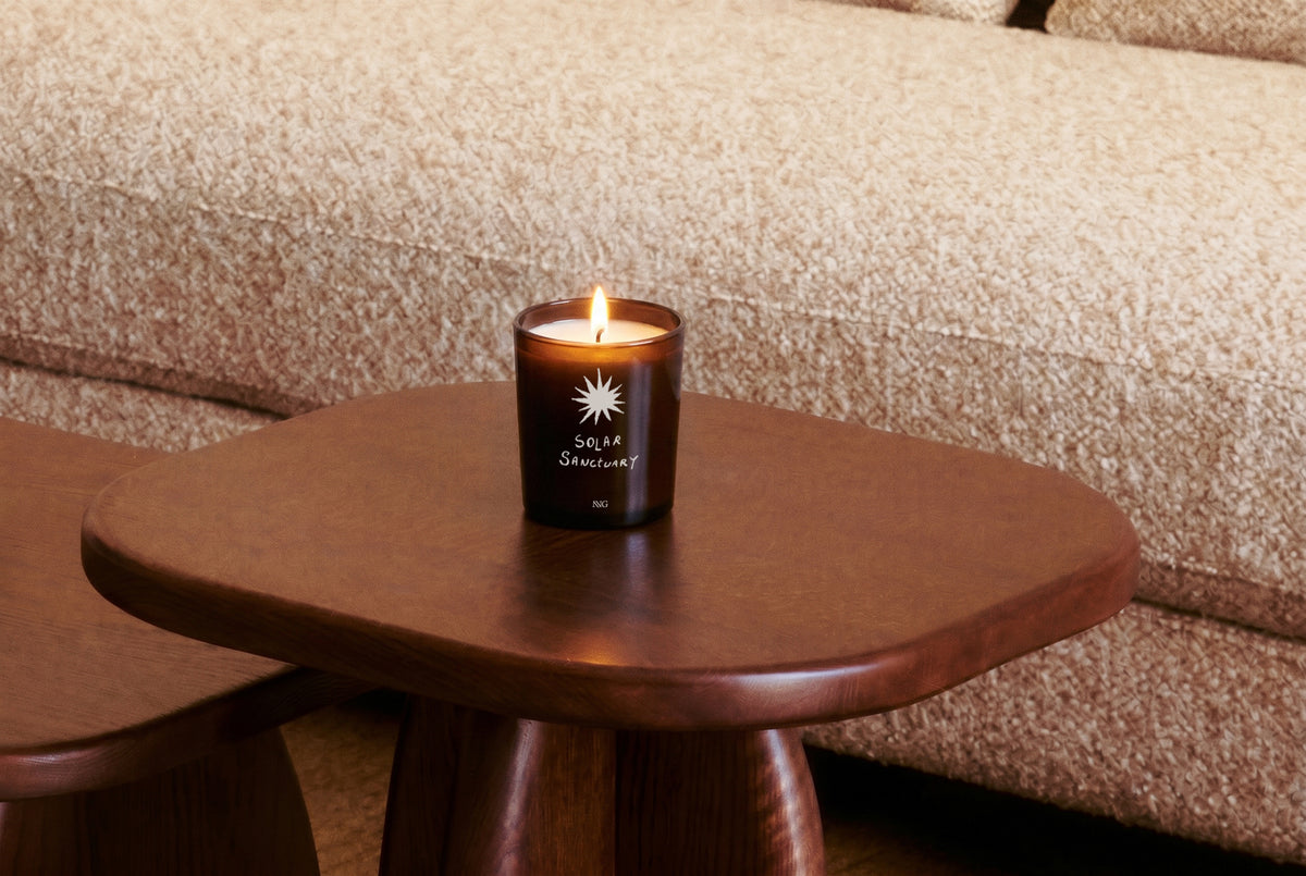 bougie Solar Sanctuary NVG x Wiwoos - verre ambré allumé - mise en situation table d'appoint bois massif